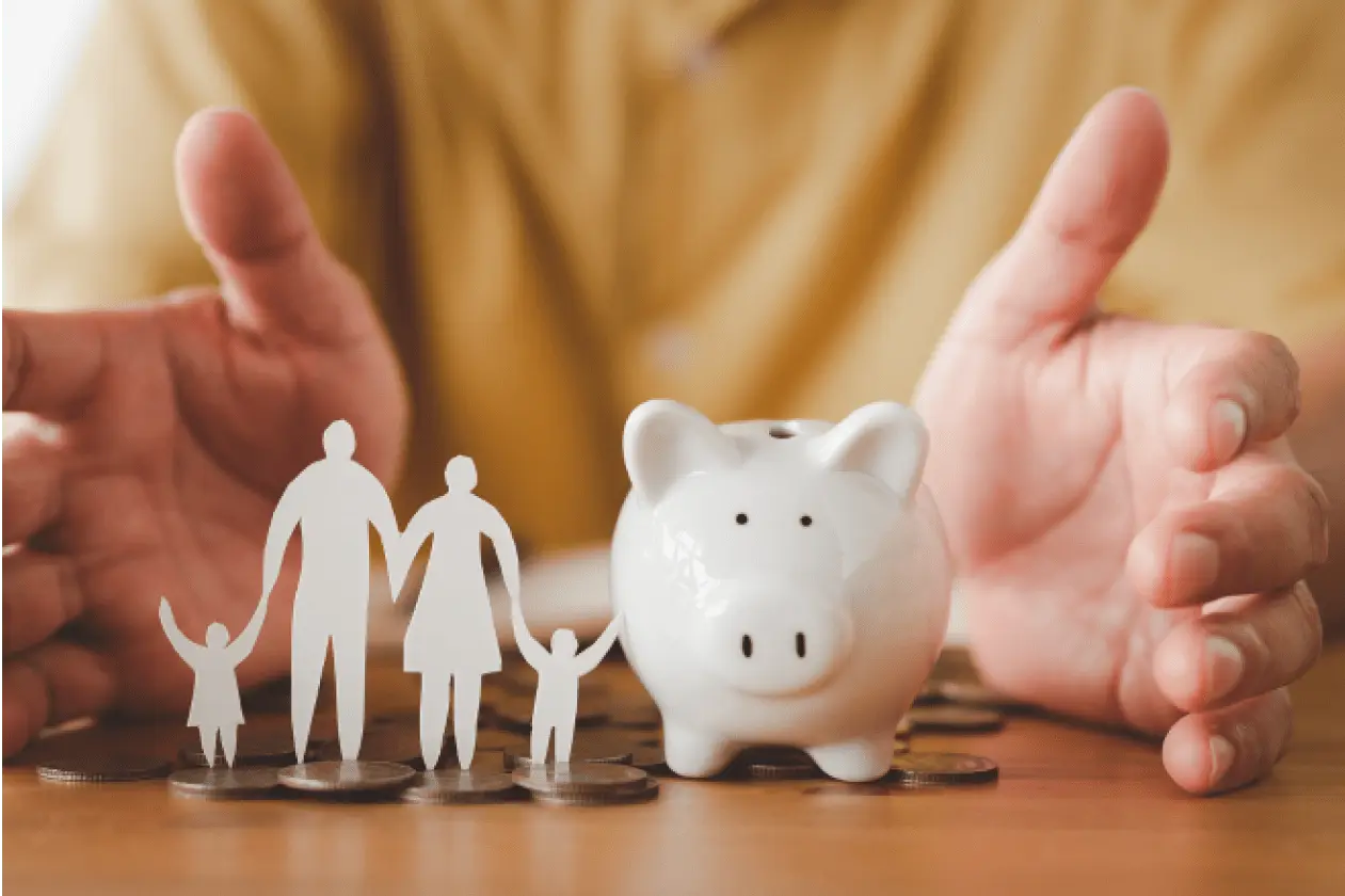 Um desenho de papel recortado de uma família (homem, mulher, um filho e uma filha), ao lado um cofre rosa em formato de porquinho e atrás uma pessoa de camisa amarela, com as mãos em volta da família e do cofrinho.